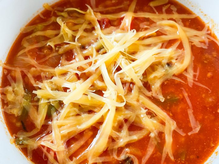 close up bowl of stuffed pepper soup topped with cheddar cheese